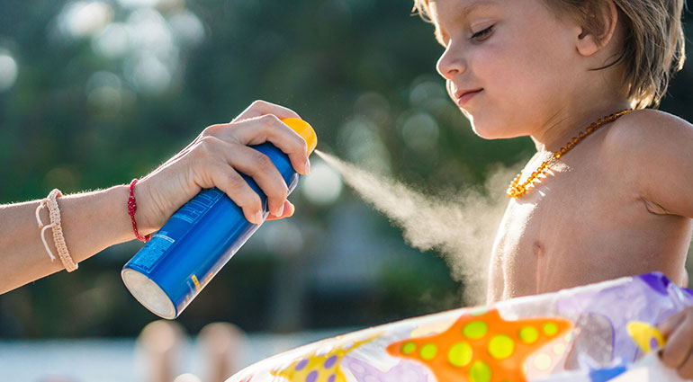 Spraying sunscreen at the beach
