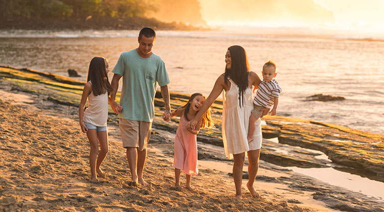 Happy family walking along the beach in Hawai‘i