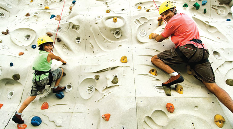 Father and son climb a rock wall on a Royal Caribbean cruise ship
